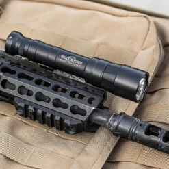 SureFire M640DFT-PRO Turbo Scout Light Pro | Dual-Fuel | 100,000 Candela -Tactical Equipment surefire m640dft pro turbo series 6 volt dual fuel scout light pro weaponlight black mounted on rifle on top of a tactical pack with molle gallery